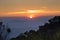 Sunset over the misty cloudy sky with tree and mountain view.