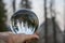 Sunset over Mountains with Forest and Moon Captured in Glass Ball Held in Palm