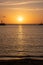 Sunset over Mykonos island, Cyclades, Greece. Lighthouse, orange yellow sky sparkle sea. Vertical