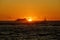 Sunset over the ocean with light reflecting on ocean waves moving with boats on the water in the distance