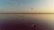 Sunset over a pink lake, a kitesurfer rushes along a calm lake