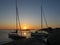 Sunset over sailboats moored at small rocky island