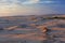 Sunset over sand dunes near the ocean.