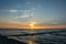 Sunset over the sea with breakwater, beach and birds