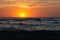 Sunset over the sea with breakwater, beach and birds