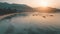 Sunset over sea and mountains. Boats on beach aerial view. Orange sun shines on calm ocean water.