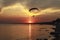 Sunset over the sea. Reflection of the sun in water. Silhouette of paraglider flying in the sky. Sunset beach in a summer evening