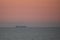 Sunset over the sea with silhouette of a container ship in the background