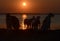 Sunset over the sea with the silhouettes of a number of dogs as foreground