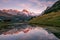 Sunset over Snowy Mountains and Wood Chalet Reflecting in Altitude Lake.