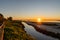 Sunset over wetlands and marshlands with a colorful sky and a sun star on the horizon