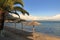 Sunset on palms and umbrellas of Ipsos Beach, Ipsos Village, Corfu Island, Greece, Europe