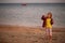 Sunset portrait of a playing caucasian toddler girl at the seashore.