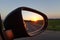 Sunset in the rearview mirror of a black car. Side mirrors.