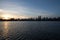 Sunset reflects on lake and silhouette buildings with blue sky