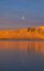 Sunset from the Reykjavik city waterfront promenade showing the full moon and the snow-capped and orange-lit islands of Engey and