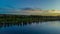 Sunset at a river on a green valley. You can see the huge river passing by, the sun behind and vegetation surrounding the landscap