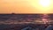 Sunset on sea beach. Small ship at the horizon.