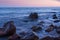 Sunset on sea. In foreground large boulders.