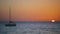 Sunset sea landscape on summer day, peaceful beach waves with boat sailing in the horizon.