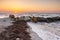 Sunset Serenity: Rocky Breakwater and Seaweed-Strewn Beach at Dusk