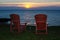 Sunset at shore with adirondack chairs