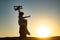 Sunset silhouette of Father carrying his son on shoulders. Boy child is sitting on daddy shoulder piggyback while the
