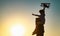 Sunset silhouette of Father carrying his son on shoulders. Boy child is sitting on daddy shoulder piggyback while the