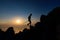 Sunset silhouette of skyrunner man climbing alpine ridge with poles