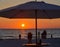 The sunset with the silhouette of an umbrella and people on the beach. This is at Indian Rocks Beach, Gulf of Mexico, Florida.