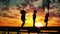 Sunset and silhouettes of happy kids jumping on the wooden pier above the lake water