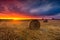 Sunset sky over field with straw bales