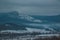 sunset snow field on top of mountain slope with frosty pine trees on the background of crimea forest and hills under grey