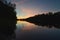 Sunset on the St. Croix River between Minnesota and Wisconsin - darkened trees reflected on the calm waters - blue, orange, pink c