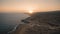 Sunset sun over rocky desert coast beach. Ocean water, orange sky, sandy seashore. Sunset viewpoint spot