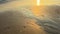 Sunset sun reflected in sea water and wet sand at golden hour. Ocean shore background. Sparkling texture of sandy beach