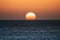 Sunset or sunrise moment over the ocean with sun touching the horizon line on the water - romantic and touristic concept for