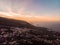 Sunset in Tenerife North with the cliff and a rock in the middle of the sea and a town. Picture by drone