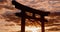 Sunset, torii gate and skies in shrine, holy place and spiritual for worship, gods and religion. Evening, prayer and