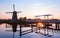 Sunset with traditional Dutch windmills and a wooden bridge in K