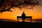 Sunset tranquility, Silhouetted man on bench exudes peaceful contemplation