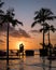 sunset tropical pool with palm trees, couple man and woman watching sunset by the pool with palm trees during vacation