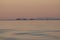 Sunset twilight ocean scene with tugboat and three barges in background