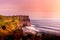 Sunset at Uluwatu temple on a cliff edge overlooking Indian Ocean with seashore on beach down below in Bali, Indonesia, Asia