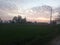 Sunset view and blue orange skyline against green field.