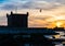 Sunset view of Essaouira fort with silhouettes of tower and gulls in Morocco