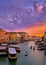 Sunset view of Grand Canal, Venice, Italy. Vaporetto or waterbus station, boats, gondolas, beautiful sunset clouds