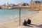 Sunset view of the Horses beach, the sea wall and the fishing port, with locals and visitors, in