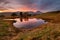Sunset view of mountain tarn with reflections at Kelly Hall Tarn in the English Lake District.