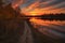 sunset view of pathway that leads to a lake with reflection of orange and yellow streaks in the sky